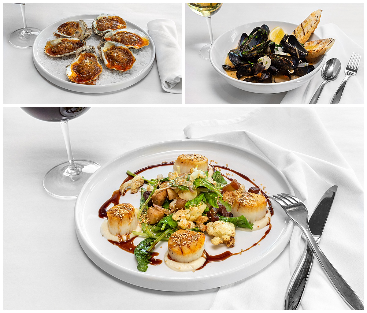 Main dishes from Jax Fish House & Oyster Bar Restaurant sit on white plates with a white tablecloth, white napkins, wine, and silverware around them.