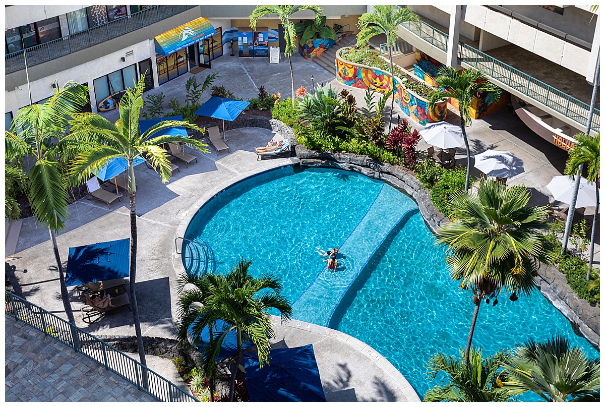 An overhead view of the adults only pool. Two people sit in the pool talking. The pool is surrounded by chairs were people can lounge.