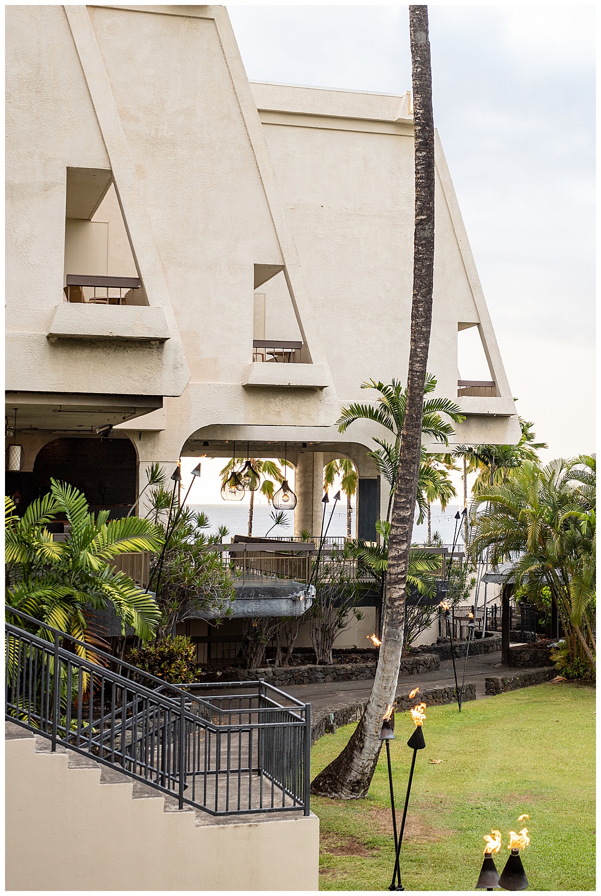 The side of the building. The rooms' lanais jut out over the lawn in a triangular shape. Under the rooms is a bar area to overlook the ocean. There is lots of plants and greenery.