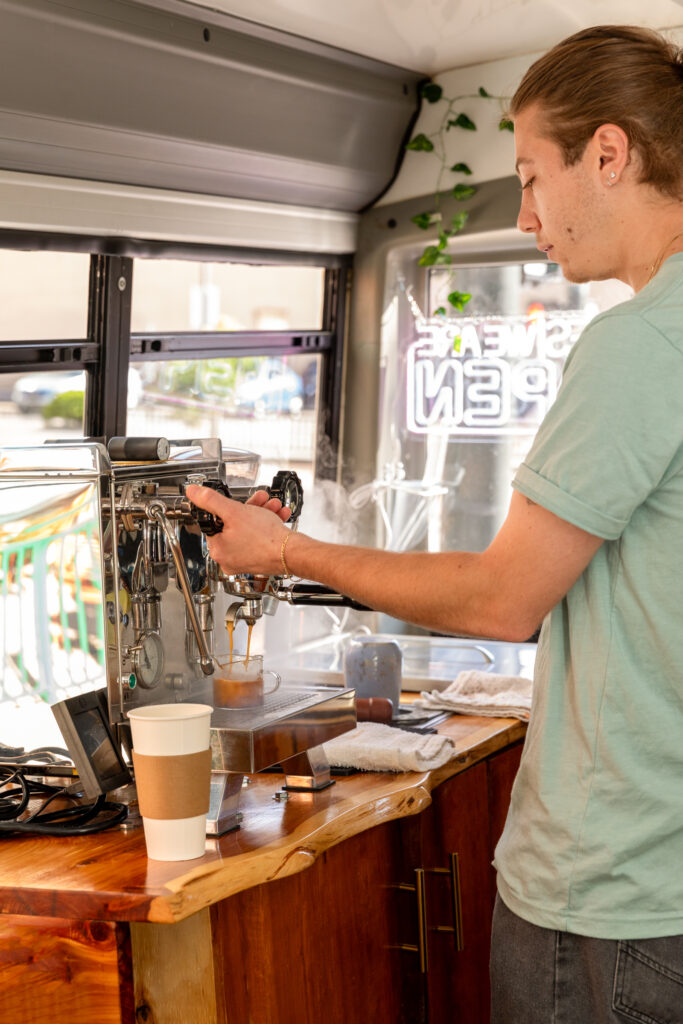 Buspresso mobile coffee truck in front of Denver cityscape